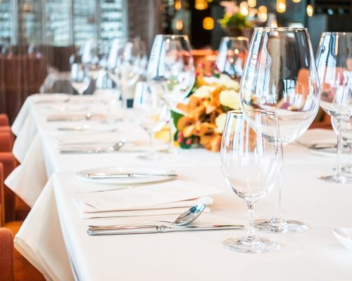 Selective focus point on wine glass with table setting for dining in restaurant